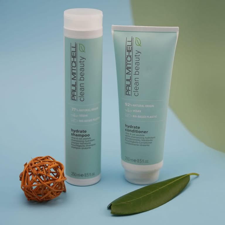Skincare bottle and matching tube arranged with a green leaf on a light blue and green background