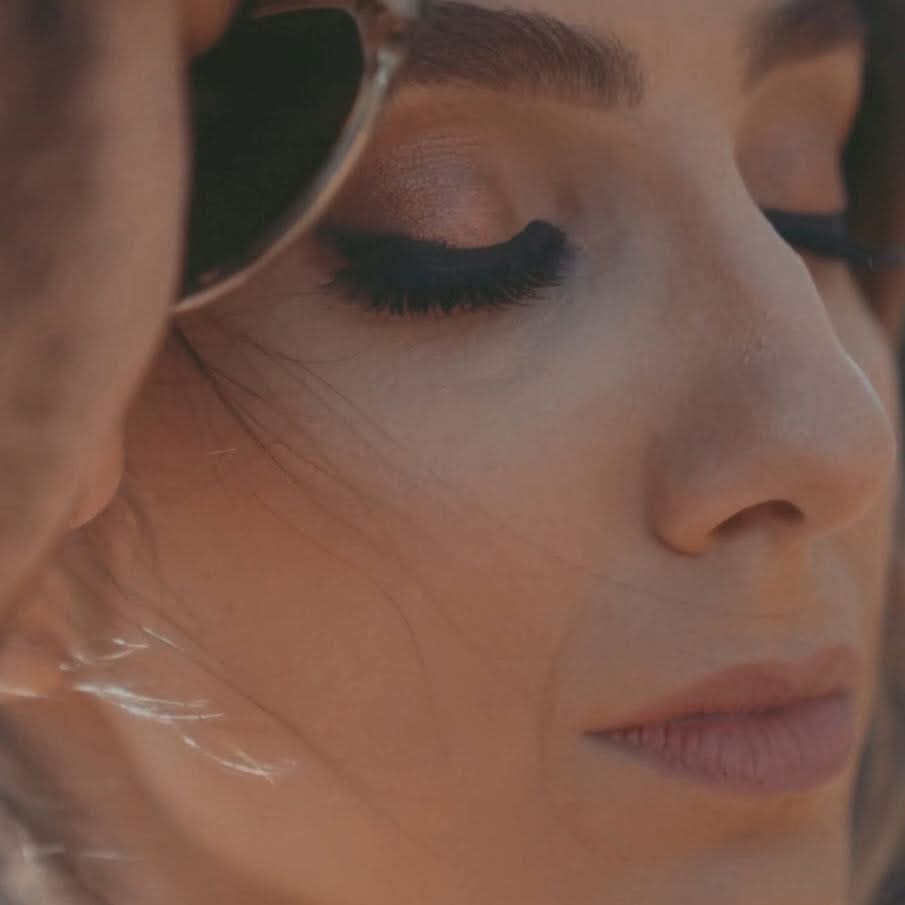 Close cinematic portrait of a woman with elegant makeup and her eyes closed during an intimate couples or lifestyle video.