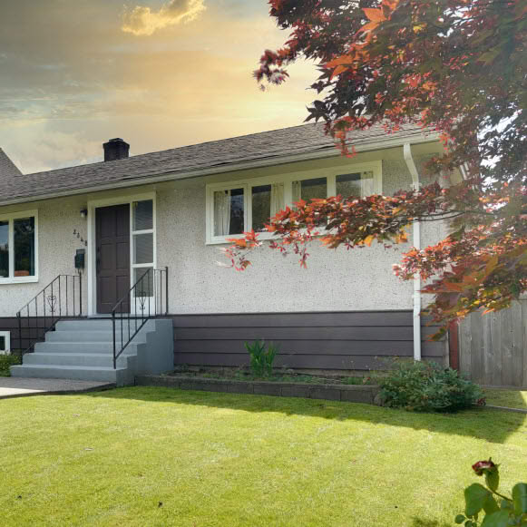 Detached residential house with a green front lawn, trees and landscaped frontage.