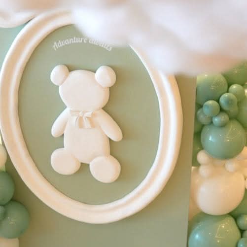 White teddy bear shaped product arranged in a green bowl with decorative green and white spheres