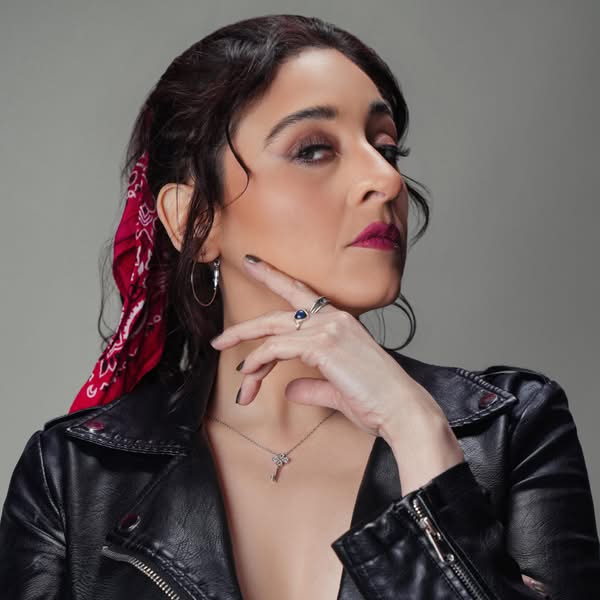 Dark haired woman wearing a black leather jacket and red hair accessories in an editorial beauty portrait