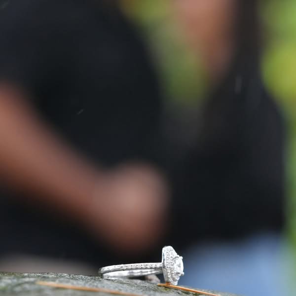 Close detail photograph of an engagement ring placed in the foreground during a proposal session