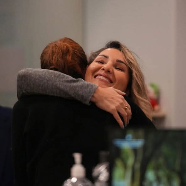 Two women sharing a warm embrace during an indoor community event