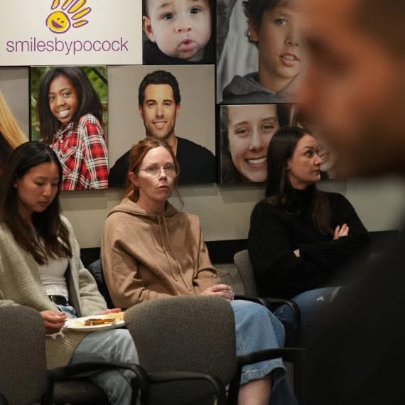 Guests seated together and talking during a community event with promotional displays in the background