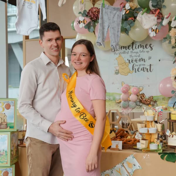 Expecting couple standing together beside a decorated display during a pregnancy celebration event
