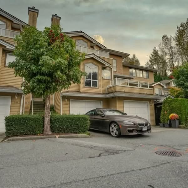 Residential townhouse exterior with driveway, garage, mature tree and neighbouring homes