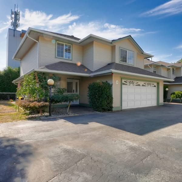Daytime exterior photograph of a large suburban home with driveway, garage and landscaped front yard