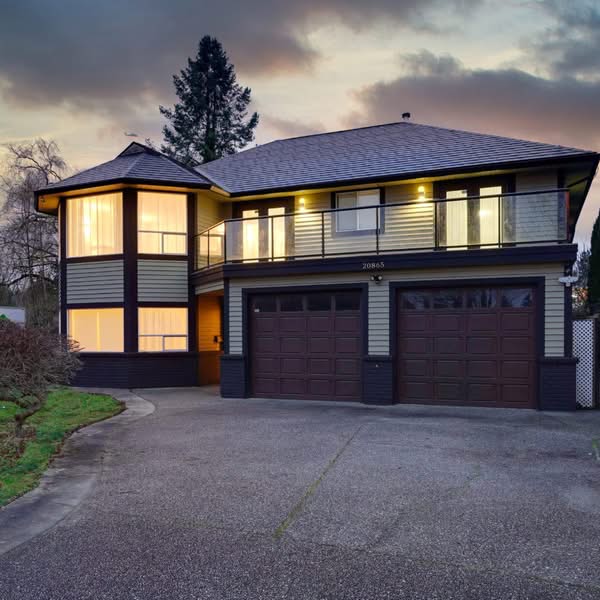Luxury two storey home illuminated at twilight with a large garage and landscaped entrance
