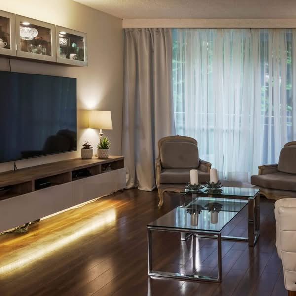 Modern living room with television, accent lighting, neutral chairs and sheer curtains