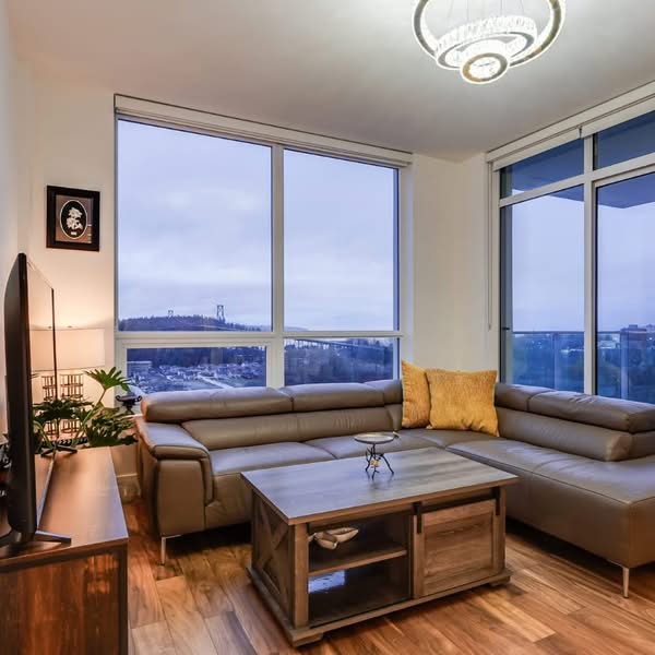 Modern condo living room with large windows, wood flooring and an elevated city view