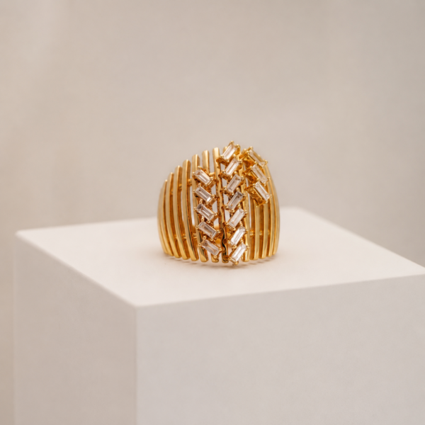Ornate gold jewellery piece displayed on a white pedestal against a warm beige background