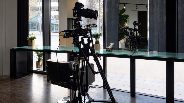 Professional cinema camera mounted on a tripod during an on location video production inside a modern building