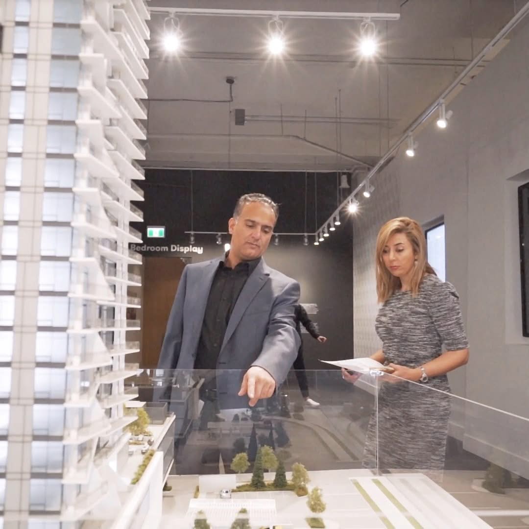 Man presenting a product demonstration while a woman holds notes inside a modern commercial showroom
