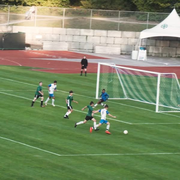 Wide elevated view of a soccer match showing players spread across the field during active play