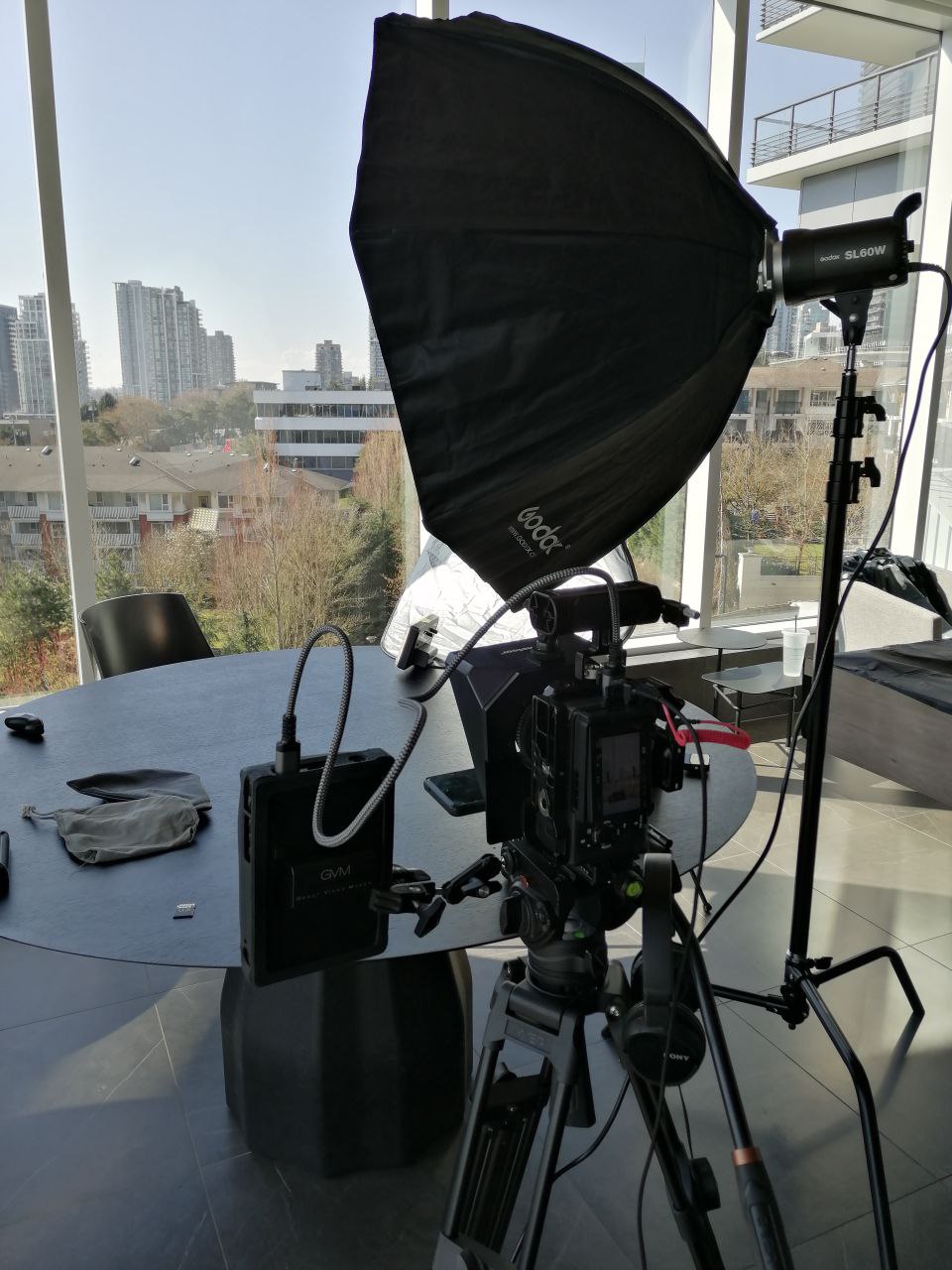 Professional video camera, tripod, softbox, video light and production monitor set up inside an office